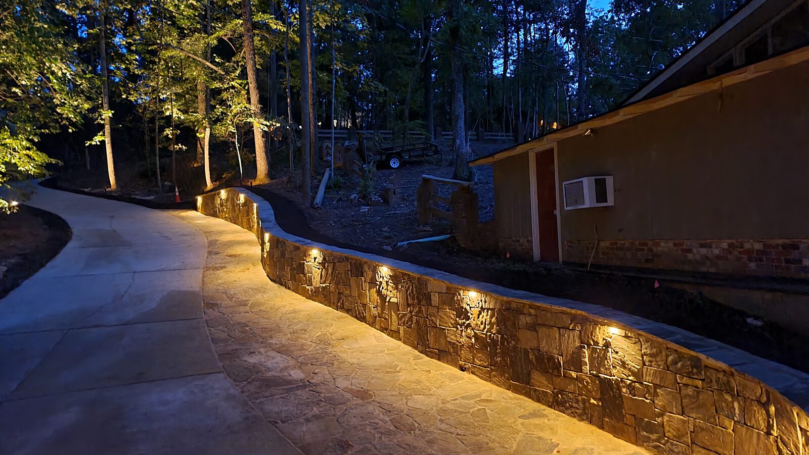 Landscape lighting illuminating a walkway and plantings at dusk